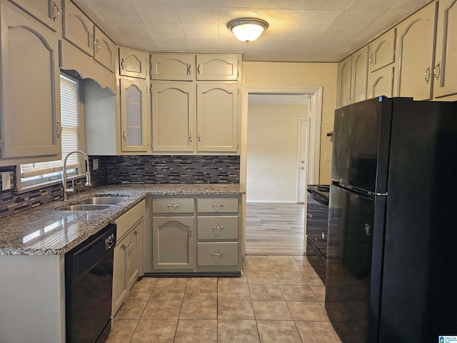 kitchen featuring tasteful backsplash, sink, black appliances, light tile patterned floors, and stone counters