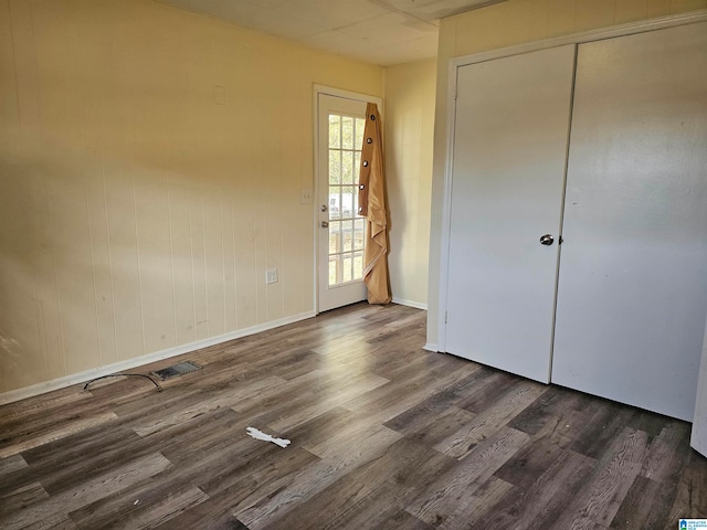 unfurnished bedroom featuring a closet and dark wood-type flooring