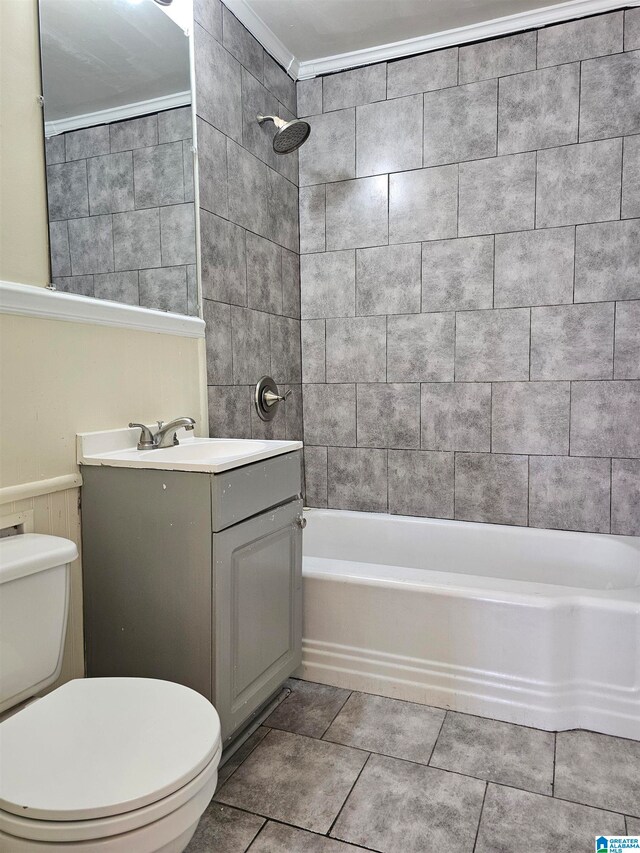 full bathroom with tile patterned flooring, crown molding, toilet, vanity, and tiled shower / bath