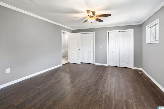 unfurnished bedroom with ceiling fan, dark hardwood / wood-style flooring, two closets, and ornamental molding