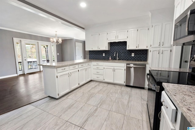 kitchen with kitchen peninsula, appliances with stainless steel finishes, sink, pendant lighting, and white cabinets