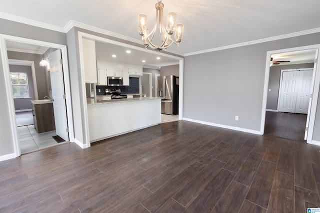 unfurnished living room with ceiling fan with notable chandelier, dark hardwood / wood-style flooring, and ornamental molding