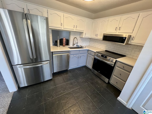 kitchen with sink, a textured ceiling, tasteful backsplash, white cabinetry, and stainless steel appliances