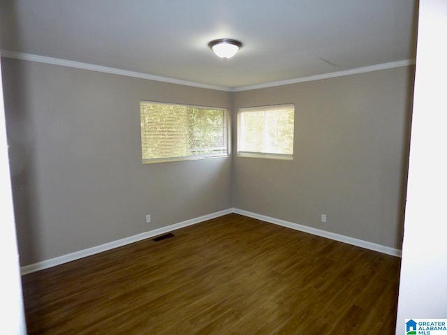 empty room featuring dark wood-type flooring and ornamental molding