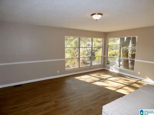 unfurnished room with hardwood / wood-style floors and a textured ceiling