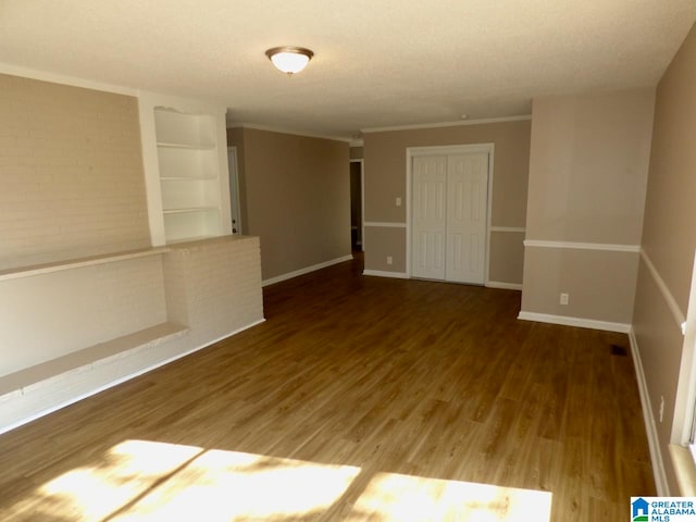 empty room featuring dark wood-type flooring, a textured ceiling, and ornamental molding