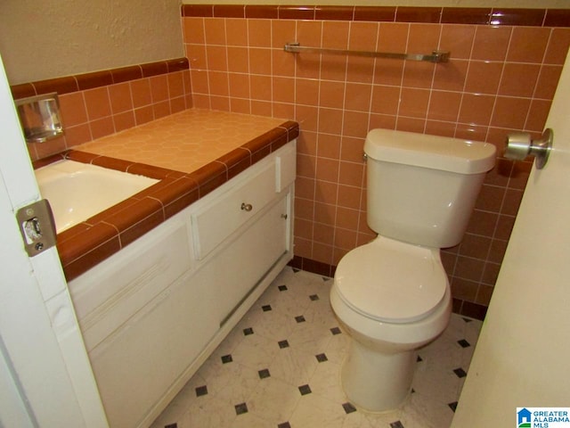 bathroom with vanity, toilet, and tile walls