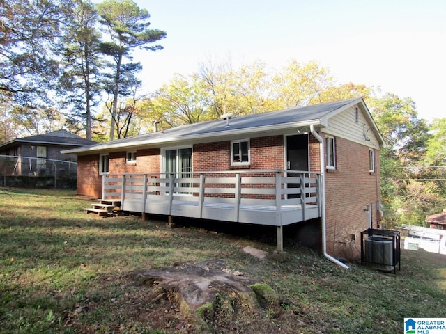 rear view of house with central AC unit, a yard, and a wooden deck