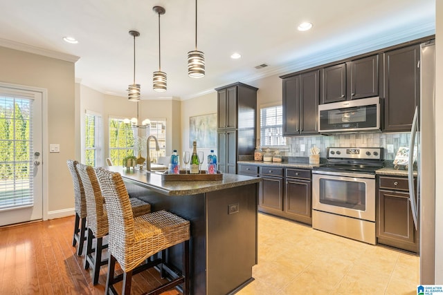 kitchen featuring pendant lighting, a center island with sink, a breakfast bar area, light wood-type flooring, and stainless steel appliances