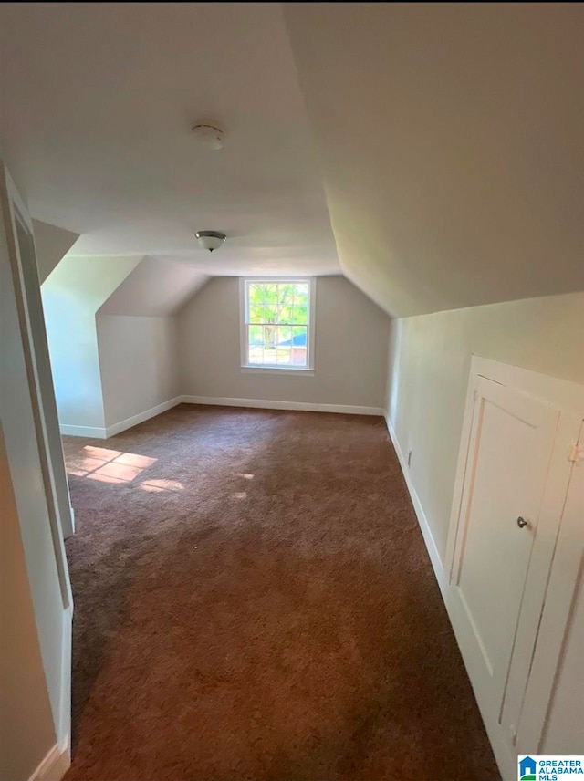 bonus room featuring dark colored carpet and lofted ceiling