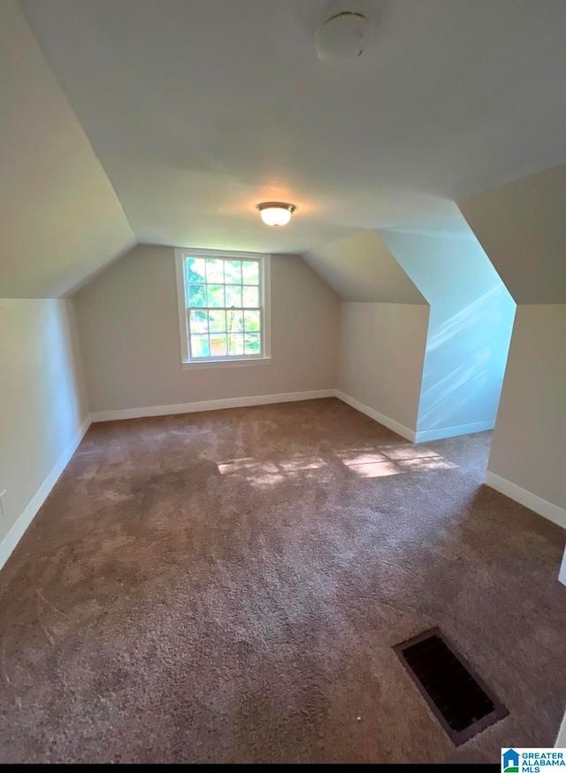 additional living space with carpet flooring and lofted ceiling