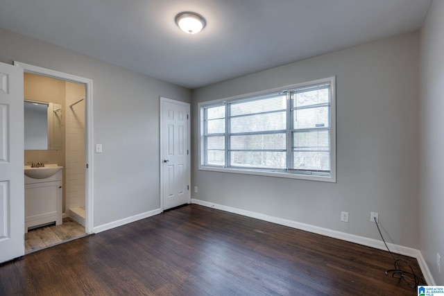 unfurnished bedroom with ensuite bath, a closet, sink, and dark hardwood / wood-style floors