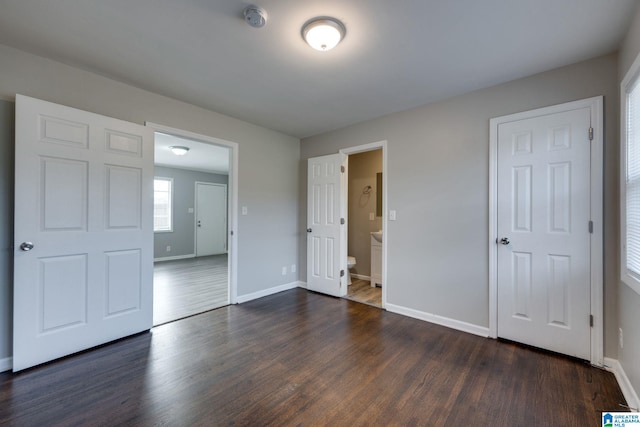 unfurnished bedroom featuring connected bathroom and dark wood-type flooring