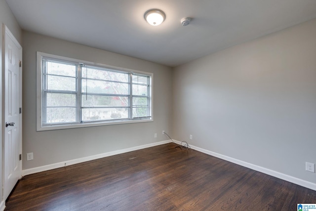 empty room featuring plenty of natural light and dark wood-type flooring