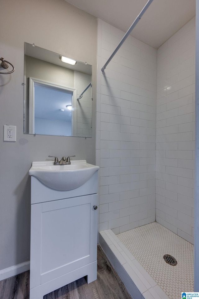 bathroom featuring hardwood / wood-style floors, vanity, and a tile shower