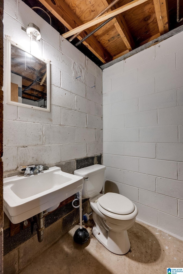 bathroom with concrete flooring, toilet, and sink