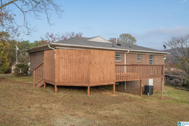 back of house featuring central AC, a deck, and a lawn