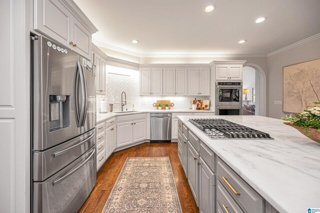 kitchen featuring appliances with stainless steel finishes, tasteful backsplash, crown molding, sink, and dark hardwood / wood-style floors