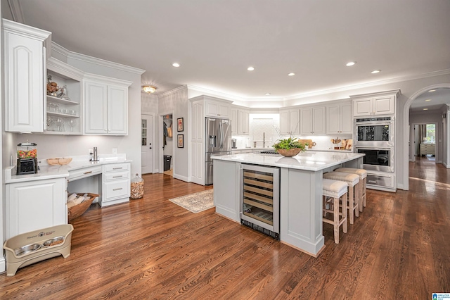 kitchen with stainless steel appliances, white cabinetry, a kitchen island, and beverage cooler