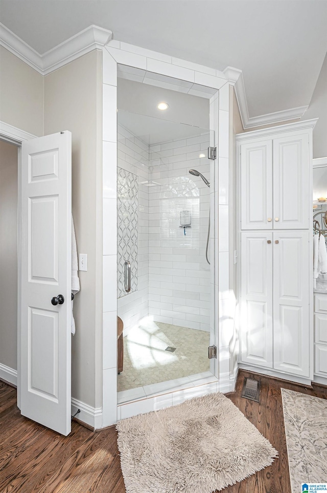 bathroom featuring hardwood / wood-style floors, an enclosed shower, and ornamental molding