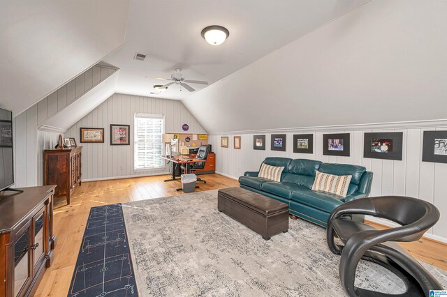 living room with hardwood / wood-style floors, wooden walls, ceiling fan, and lofted ceiling