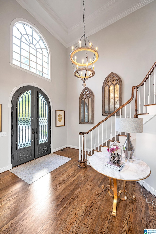 entrance foyer with a chandelier, french doors, wood-type flooring, and ornamental molding