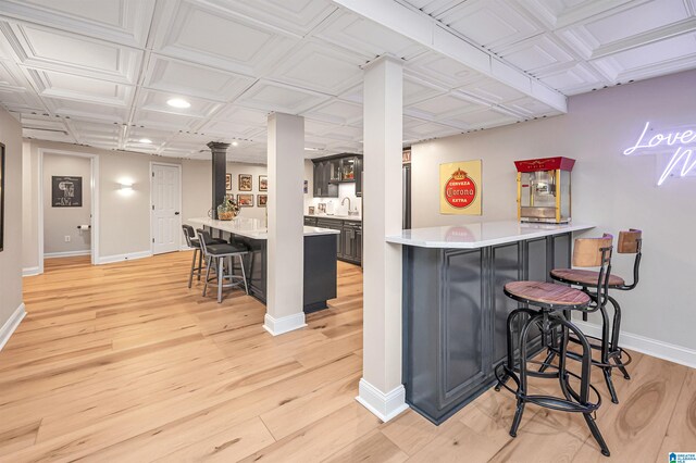 kitchen featuring a kitchen bar, kitchen peninsula, sink, and light hardwood / wood-style flooring