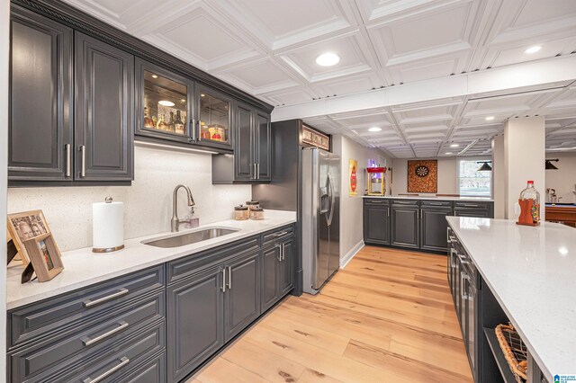 kitchen with coffered ceiling, sink, stainless steel refrigerator with ice dispenser, and light wood-type flooring