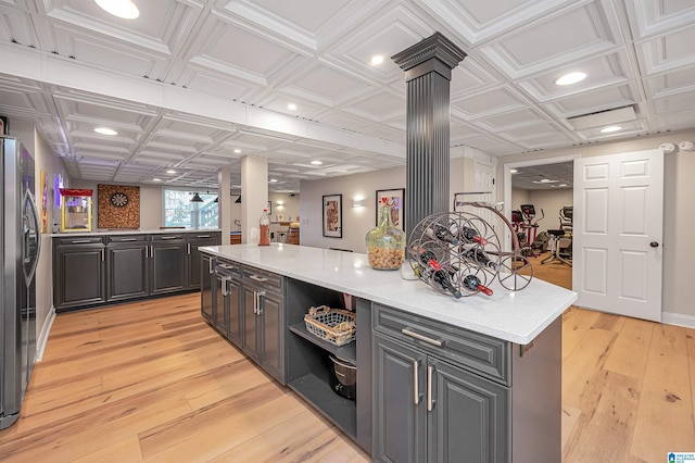 kitchen with a center island, light hardwood / wood-style floors, ornate columns, and stainless steel refrigerator