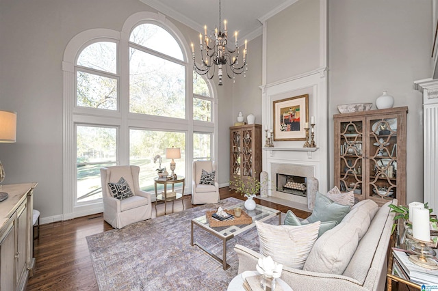 living room featuring dark hardwood / wood-style flooring, a towering ceiling, crown molding, and a chandelier