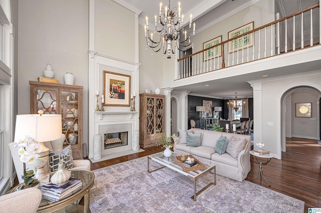 living room with dark hardwood / wood-style flooring, crown molding, a high ceiling, and decorative columns