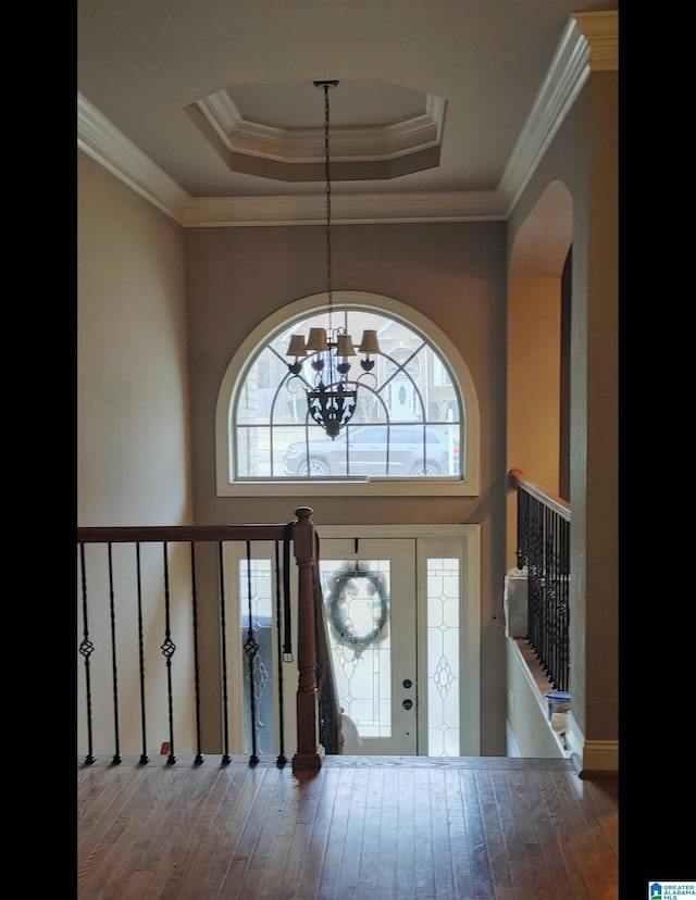 entrance foyer with a raised ceiling, crown molding, a notable chandelier, and hardwood / wood-style flooring