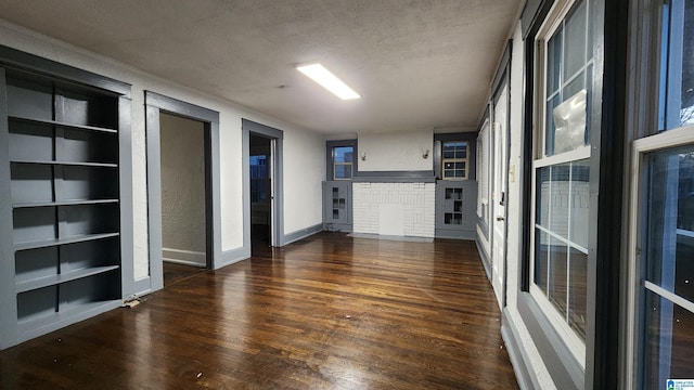 unfurnished living room featuring a textured ceiling, built in features, and dark hardwood / wood-style floors