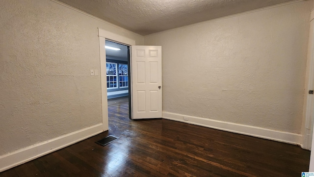 empty room featuring a textured ceiling and dark wood-type flooring