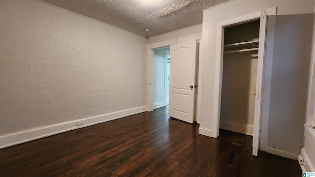 unfurnished bedroom featuring a textured ceiling, dark hardwood / wood-style flooring, and a closet