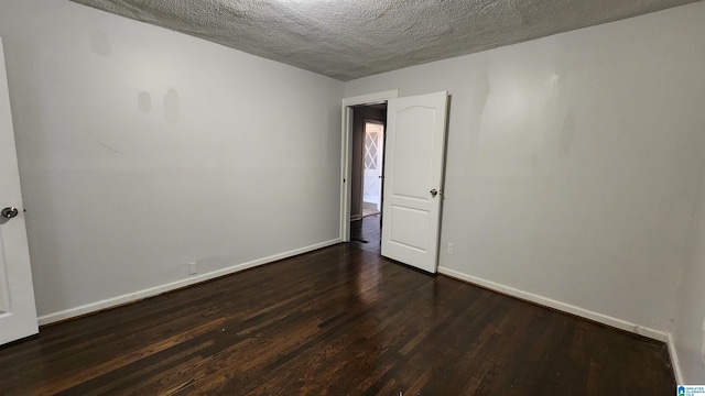 spare room featuring a textured ceiling and dark hardwood / wood-style flooring