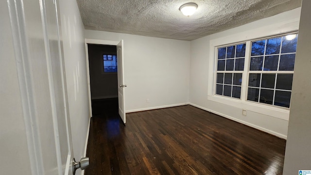 unfurnished room with a textured ceiling and dark hardwood / wood-style floors