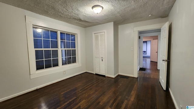 empty room with a textured ceiling and dark wood-type flooring