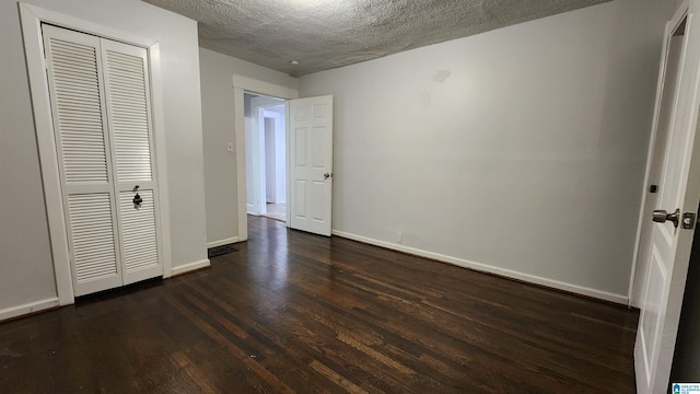 unfurnished bedroom with a textured ceiling, a closet, and dark hardwood / wood-style floors