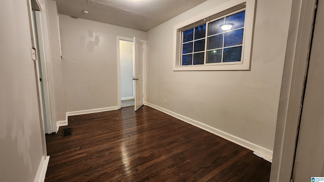 empty room featuring a textured ceiling and dark wood-type flooring