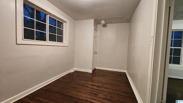 empty room featuring a textured ceiling and dark hardwood / wood-style floors