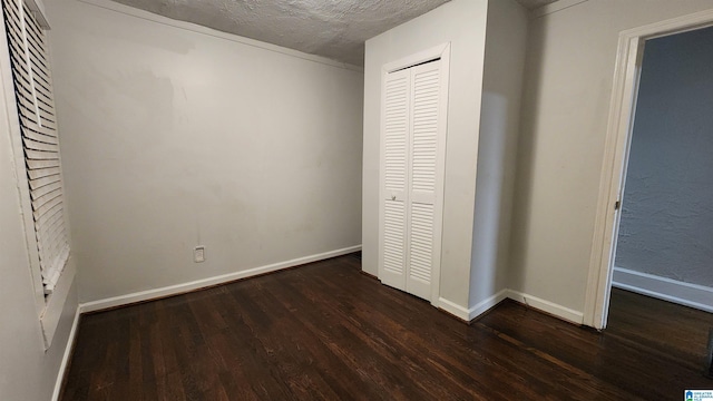 unfurnished bedroom featuring a textured ceiling, dark hardwood / wood-style flooring, and a closet