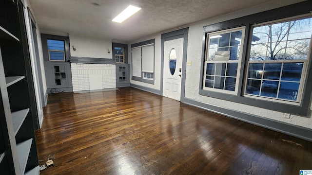 unfurnished living room featuring a textured ceiling and dark wood-type flooring