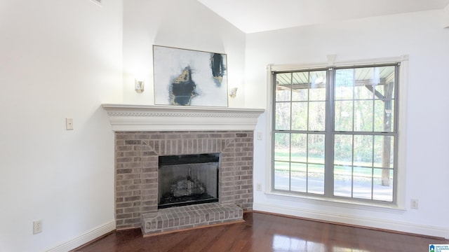 unfurnished living room with dark wood-type flooring, lofted ceiling, and a brick fireplace