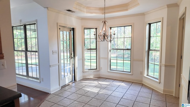 entryway with a raised ceiling, a healthy amount of sunlight, and a notable chandelier