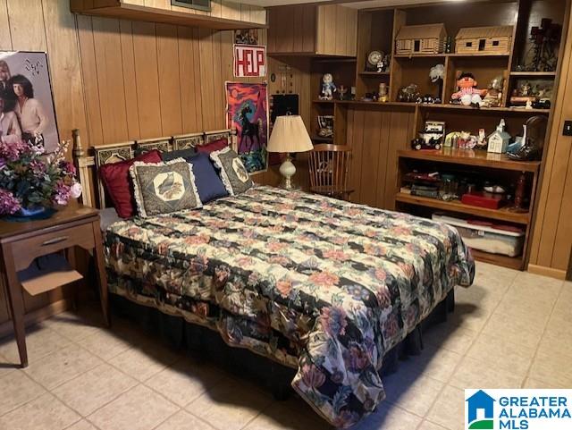 bedroom with wood walls and light tile patterned floors