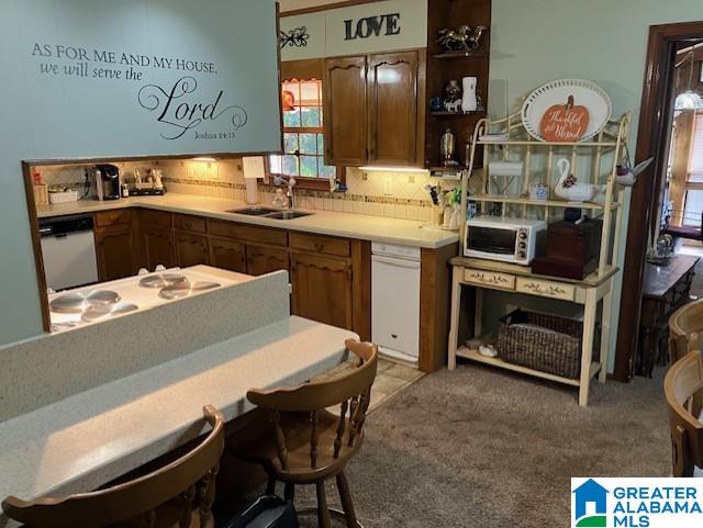 kitchen featuring backsplash, sink, light colored carpet, and white appliances