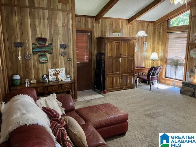 sitting room featuring vaulted ceiling with beams, wood walls, and light colored carpet