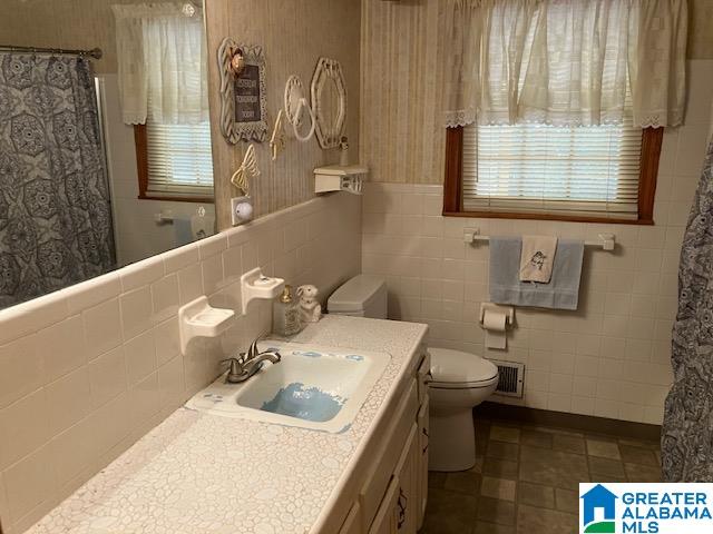 bathroom featuring vanity, toilet, and tile walls