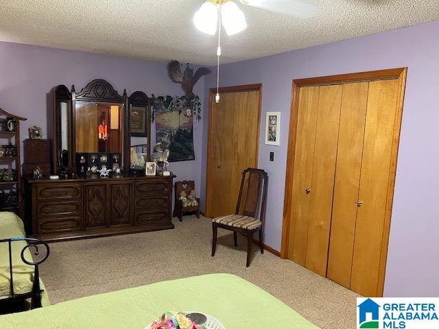 bedroom with ceiling fan, a closet, light colored carpet, and a textured ceiling